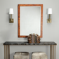 Console table with decorative items, mirror, and wall sconces against a gray wall.