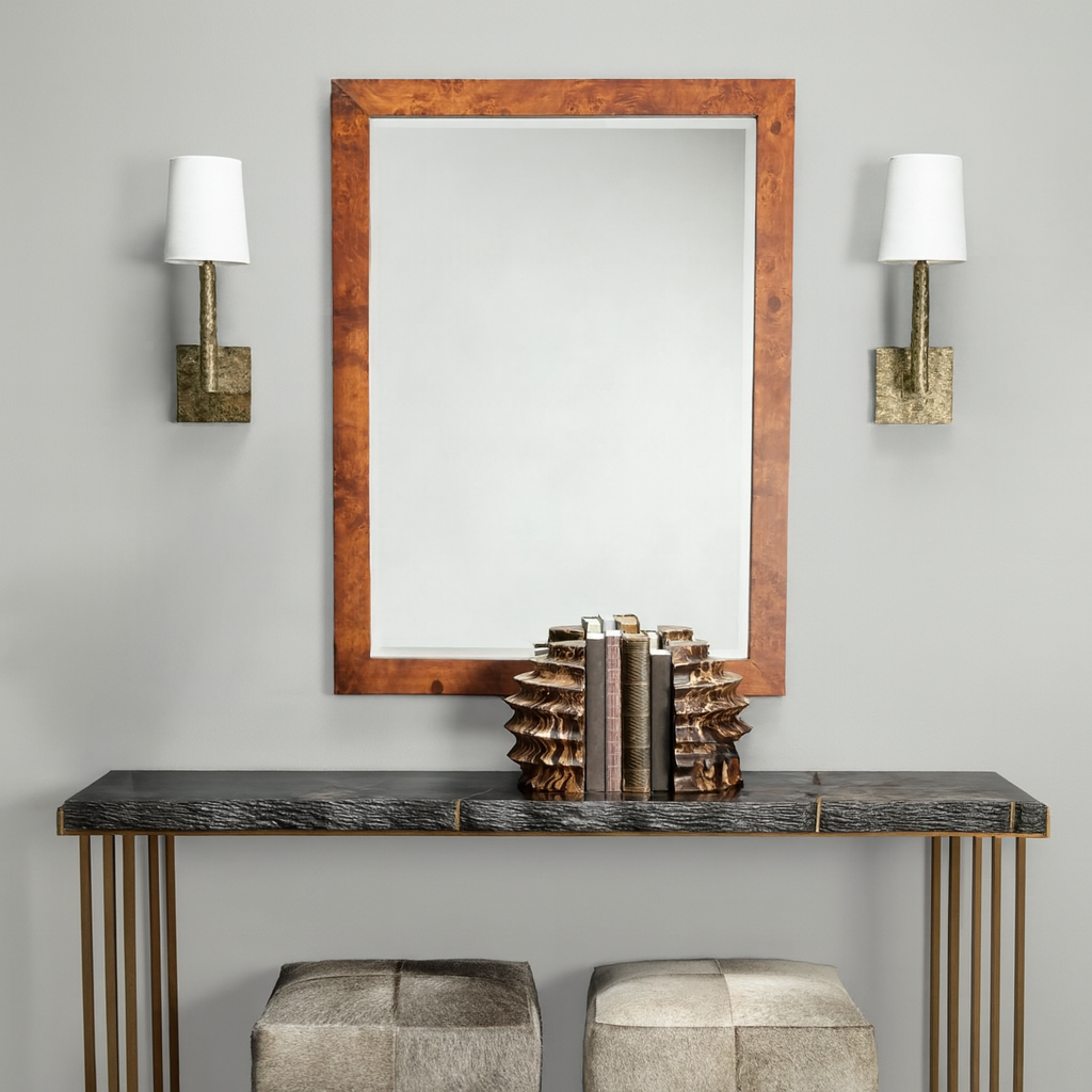 Console table with decorative items, mirror, and wall sconces against a gray wall.