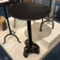 Black round table with a unique base design on a display platform