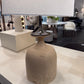 Table lamp with a textured base and white shade on a table in an indoor setting.