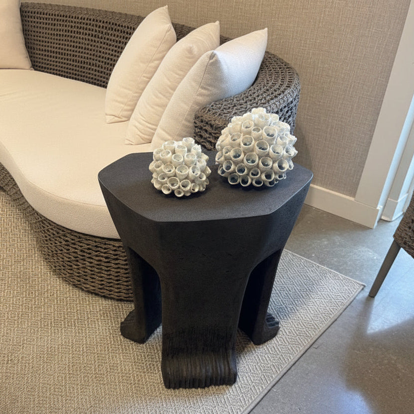 Black side table with decorative items next to a white sofa in a living room setting.