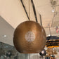 Bronze spherical pendant light hanging from a ceiling in a store setting.