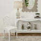 Decorative interior setting with a white chair, lamp, and table with decorative items.