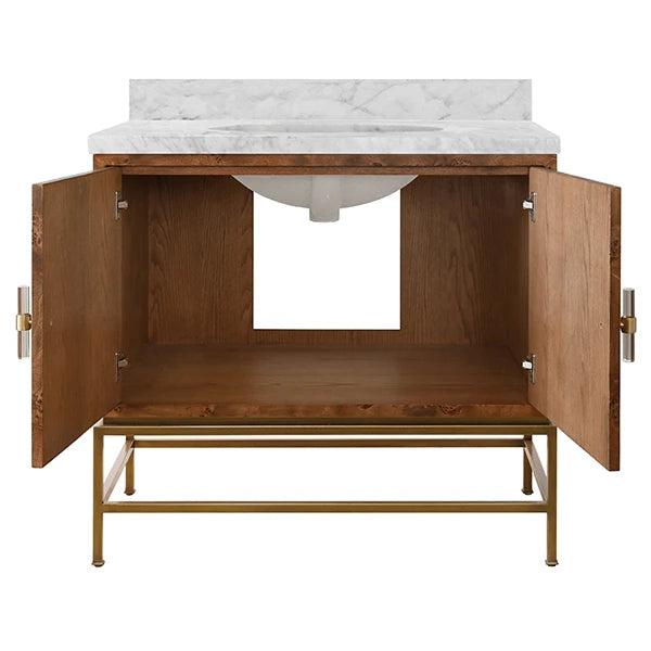 A modern bathroom vanity cabinet with a warm medium-brown wood finish, open doors, a white marble countertop, and a gold-finished metal frame, shown on a plain white background.