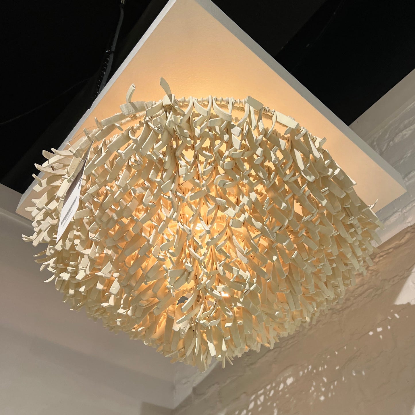 Decorative wall light fixture casting a shadow on a textured wall.