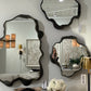 Three decorative mirrors on a wall with a neutral background