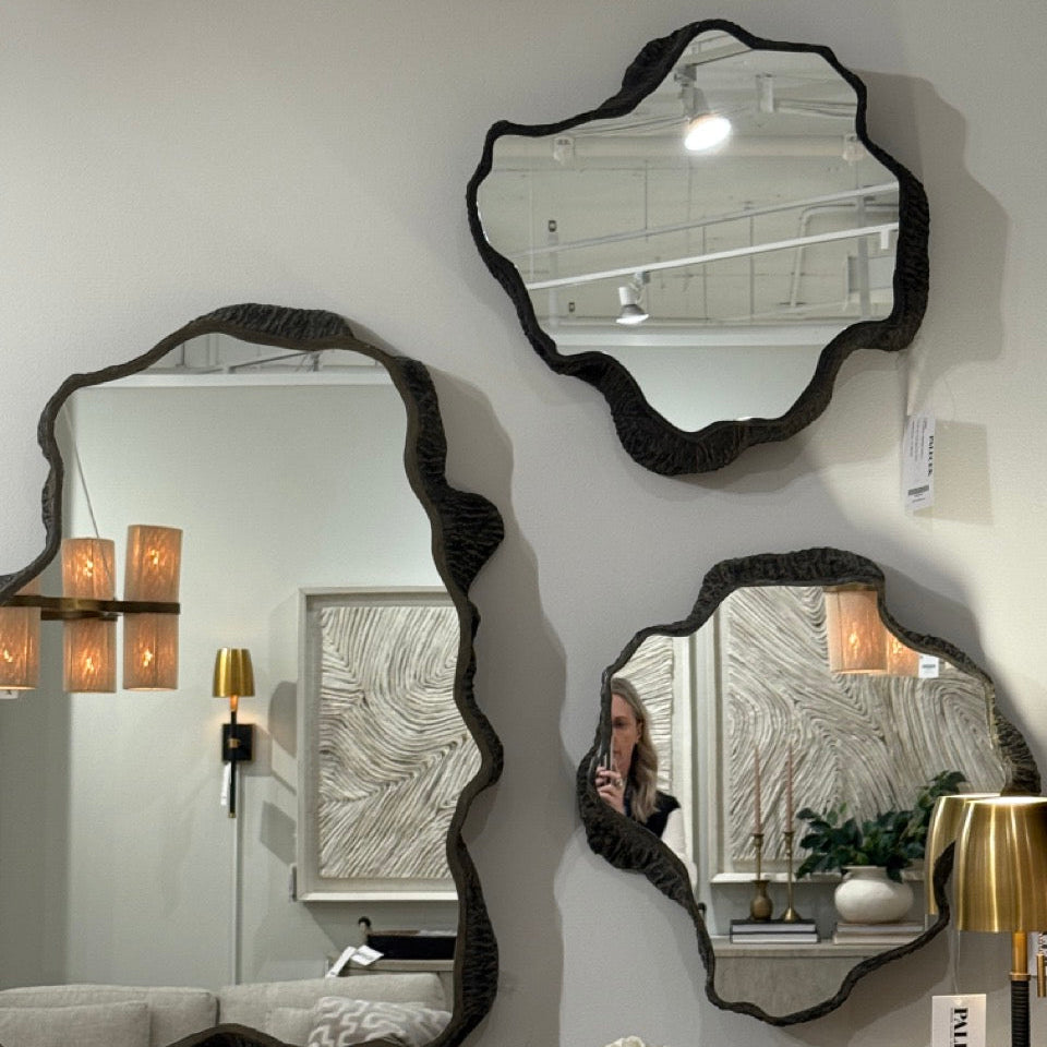 Three decorative mirrors on a wall with a neutral background