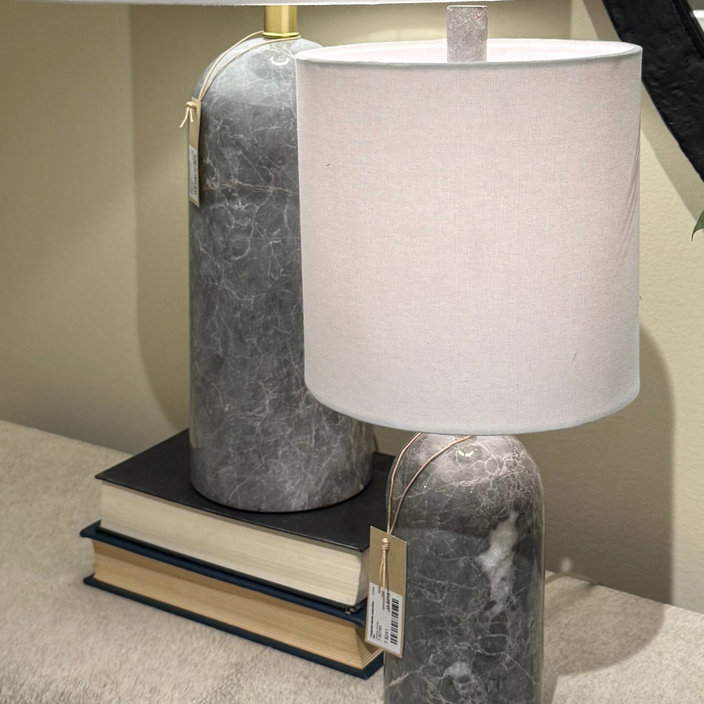 Two table lamps with marble bases and white shades on a surface.