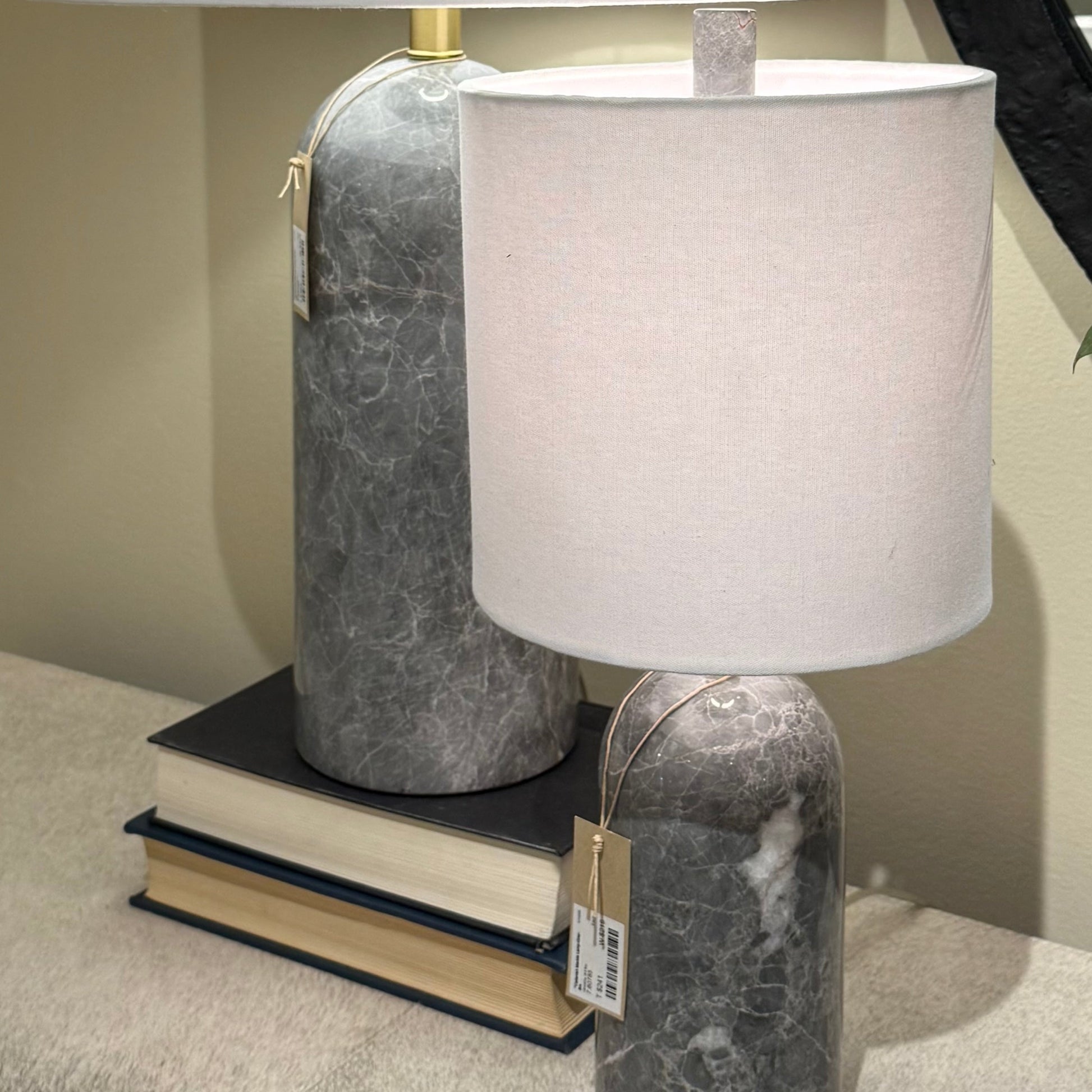 Two table lamps with marble bases and white shades on a surface.