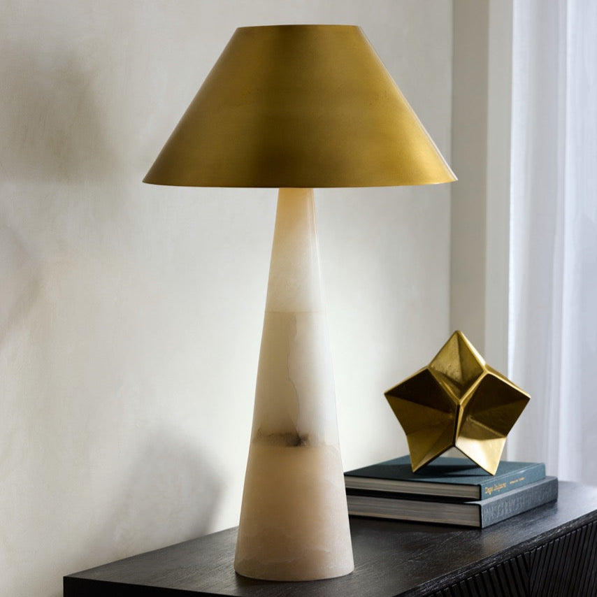 Decorative table lamp with a gold shade on a dark surface against a light background