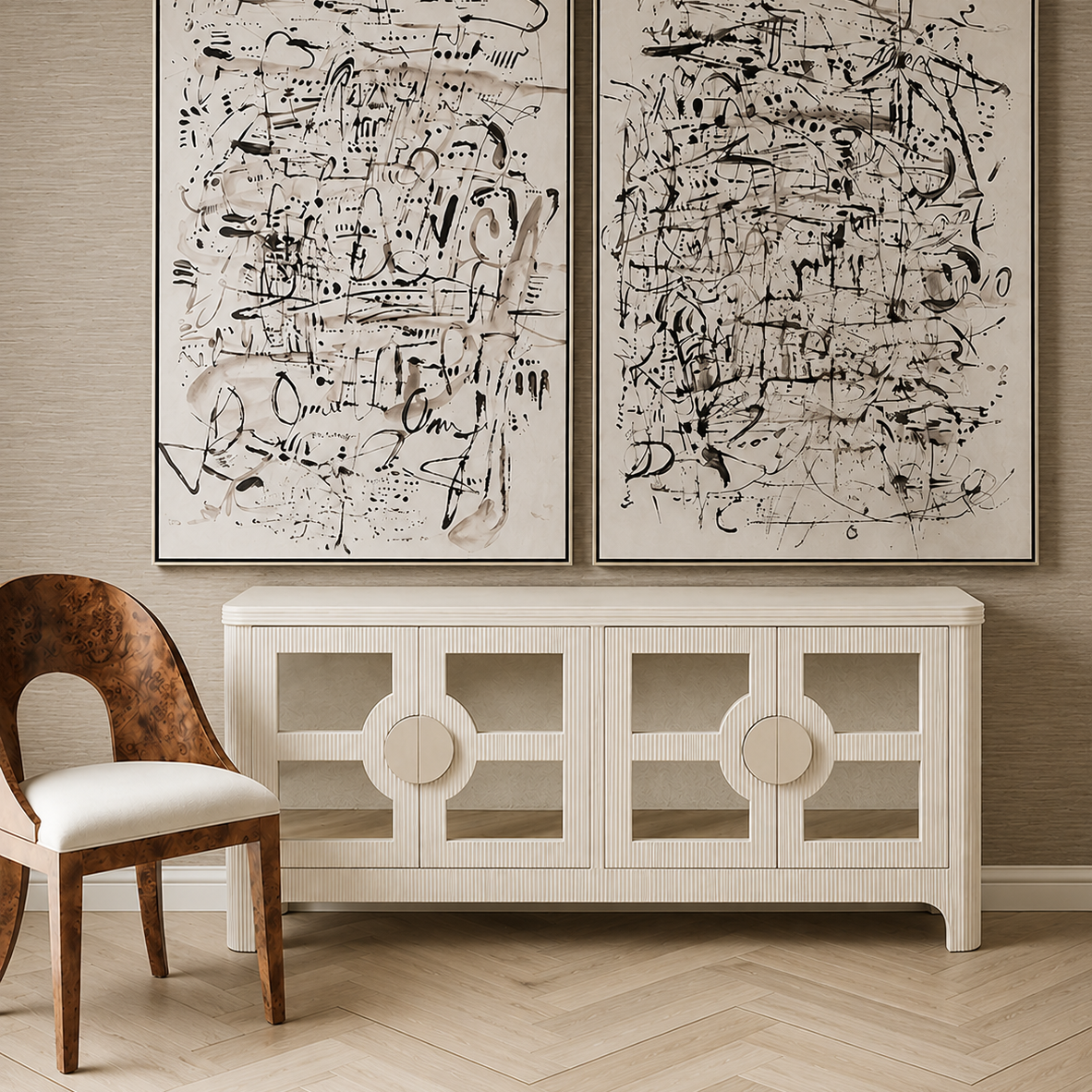A styled interior scene showing two large framed abstract black-and-white canvases mounted on a beige wall above a white sideboard, with a wooden chair partly visible in the foreground.