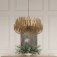 A modern multi-light chandelier with a bronze metal frame and warm gold-toned glass shades, hanging in front of a white paneled wall above a console table with a potted green plant.