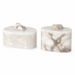 Two oval marble decorative boxes with matching lids, one in light beige marble and one in white marble with tan veining, each topped with a rough natural stone piece, on a white background.
