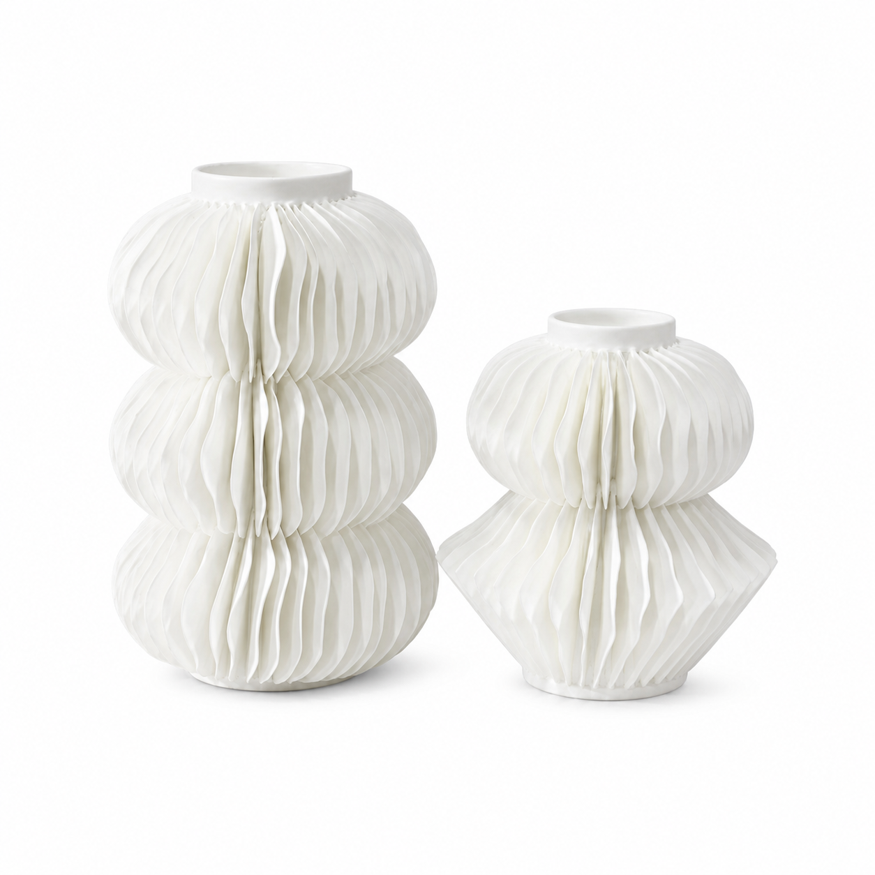 Two white ceramic decorative vases with a pleated, accordion-like textured design, one standing upright and one sitting upright, on a seamless white background.