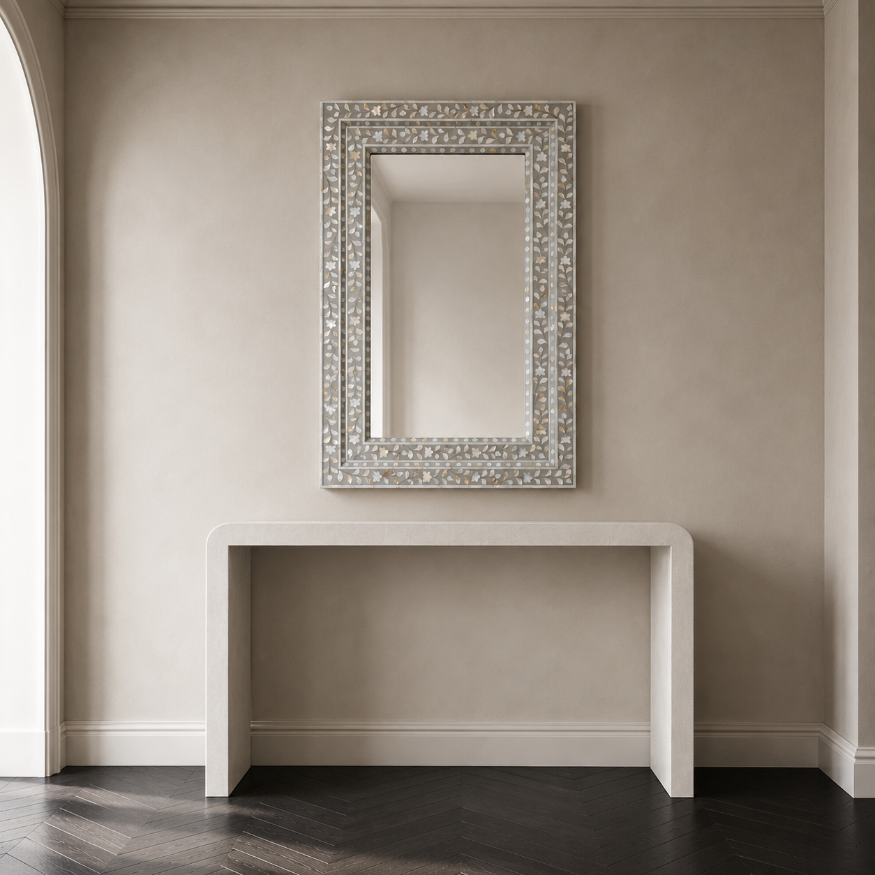 A rectangular wall mirror with an ornate silver mosaic frame, mounted on a beige wall above a white console table.