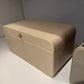 Beige leather jewelry box on a white surface with a gray background