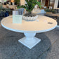 Round white table with a plant on a gray floor in an indoor setting