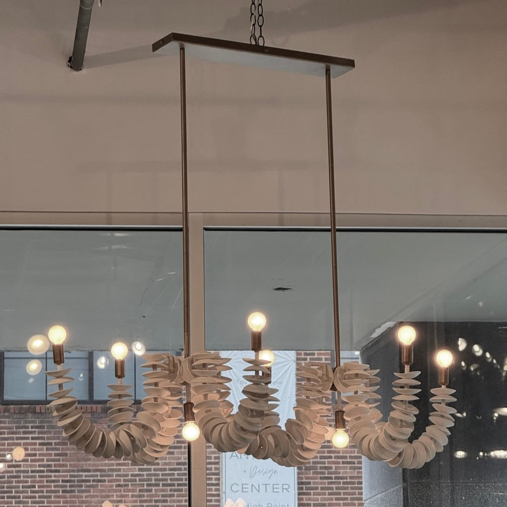 Modern chandelier hanging in a room with glass walls and brick wall background