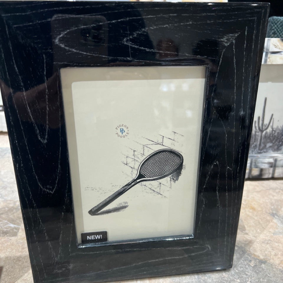 Framed picture of a tennis racket with 'NEW!' label on a textured surface