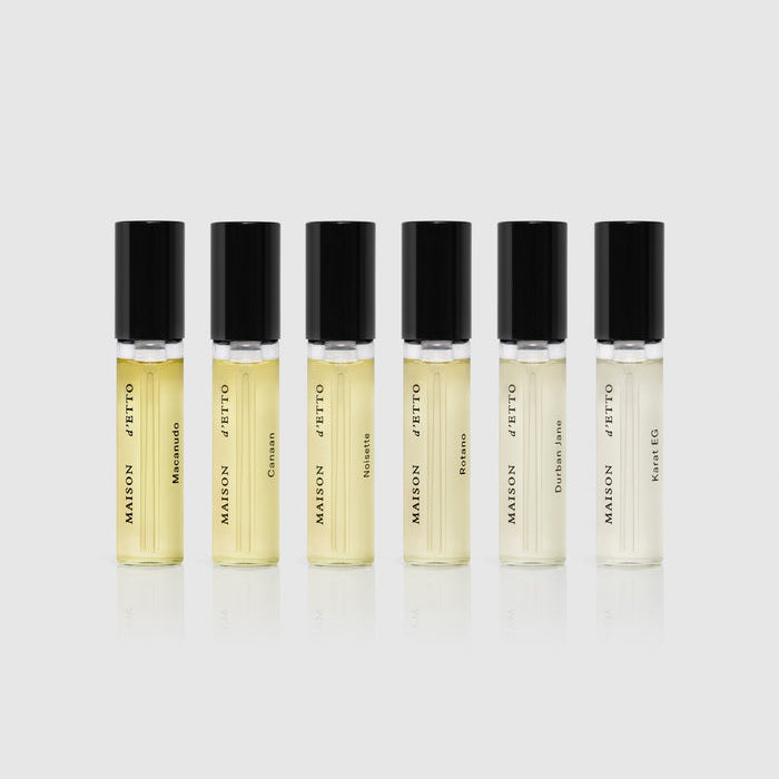 Six small perfume bottles with black caps on a light gray background