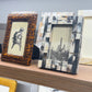 Three decorative picture frames on a shelf with a neutral background