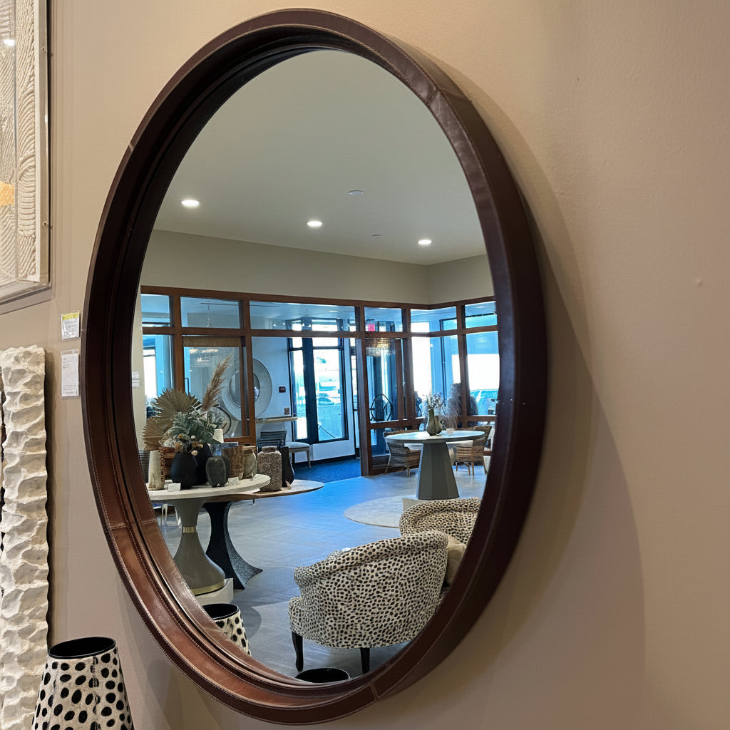 Round mirror with a leather frame in a showroom