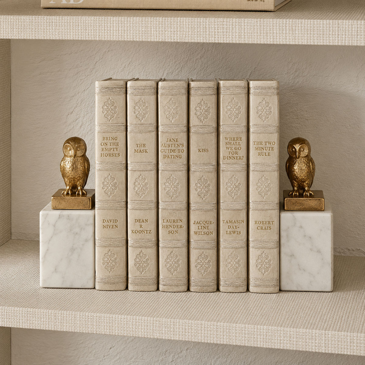 2 owl bookends gold leaf and marble holding up either side of a stack of decorative neutral books