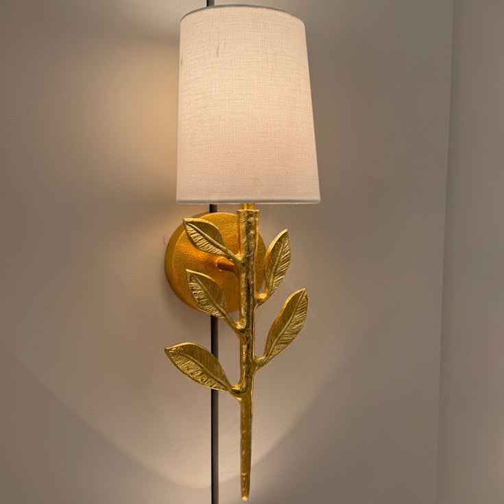 Decorative wall lamp with gold leaf design on a neutral background