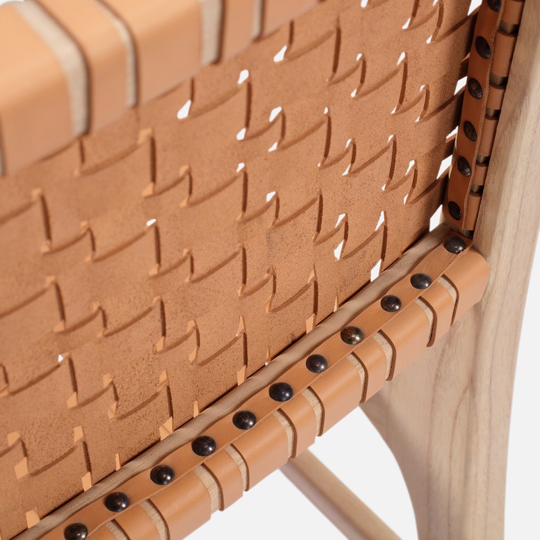 Close-up of a woven leather chair with wooden frame on a white background