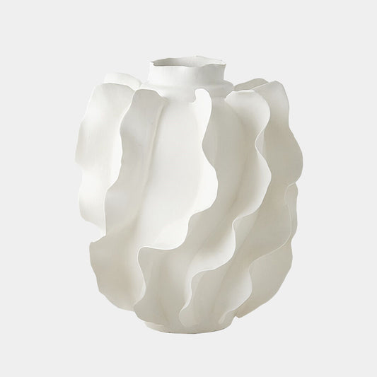 A white sculptural ceramic vase with a wavy, layered petal-like design, shown against a solid light gray background.