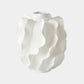 A white sculptural ceramic vase with a wavy, layered petal-like design, shown against a solid light gray background.