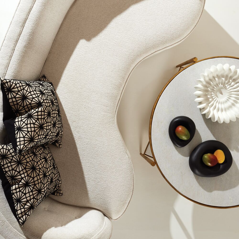 Round coffee table with decorative items on a beige sofa with patterned cushions
