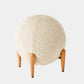 Round ottoman with textured beige cushion and wooden legs on a white background