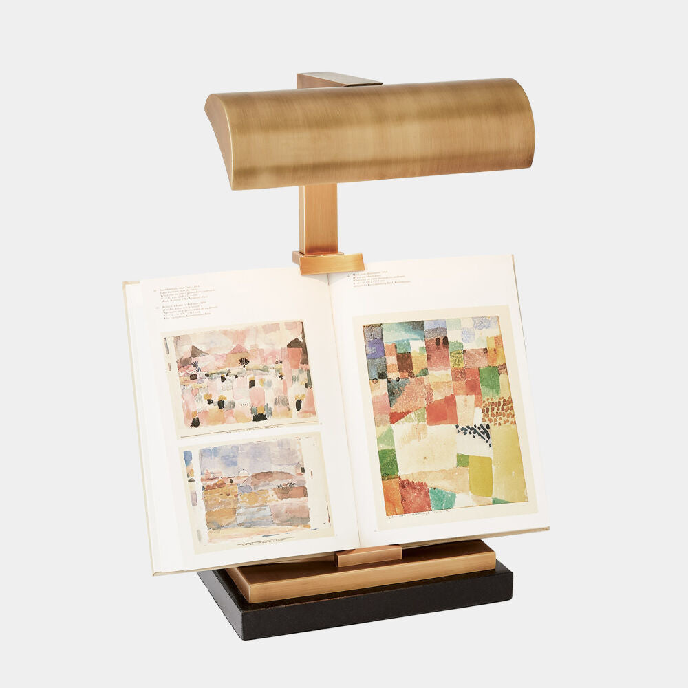 Gold book stand holding open books with colorful pages on a white background