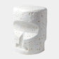 A modern sculptural side stool with a textured, organic shape resembling a stylized face, finished in white with natural beige stone flecks, set against a light gray background.