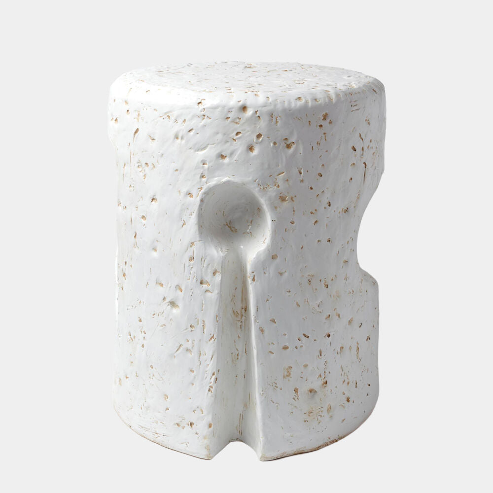 A modern cylindrical side table with a textured, speckled white finish and a central spoon-shaped cutout, shown on a light gray background.