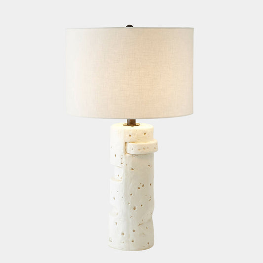 Table lamp with textured ceramic base and beige lampshade on a white background