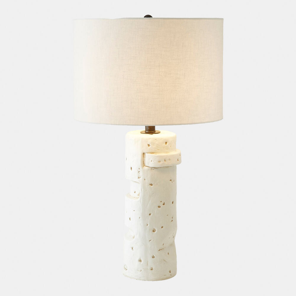 Table lamp with textured ceramic base and beige lampshade on a white background