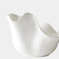 White ceramic bowl with wavy design on a light gray background