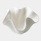 White ceramic vase with wavy design on a white background