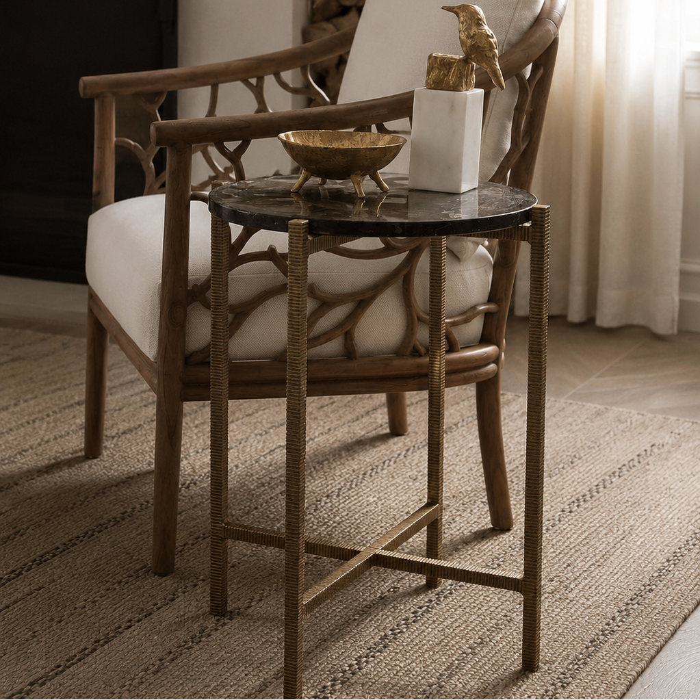 A luxury accent chair with a natural wood frame, white cushions, and a black marble-top side table styled in a bright, modern living room.