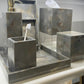Gray marble bathroom vanity set including a soap dispenser, toothbrush holder, tissue box cover, and storage box on a matching tray, displayed on a bathroom shelf.