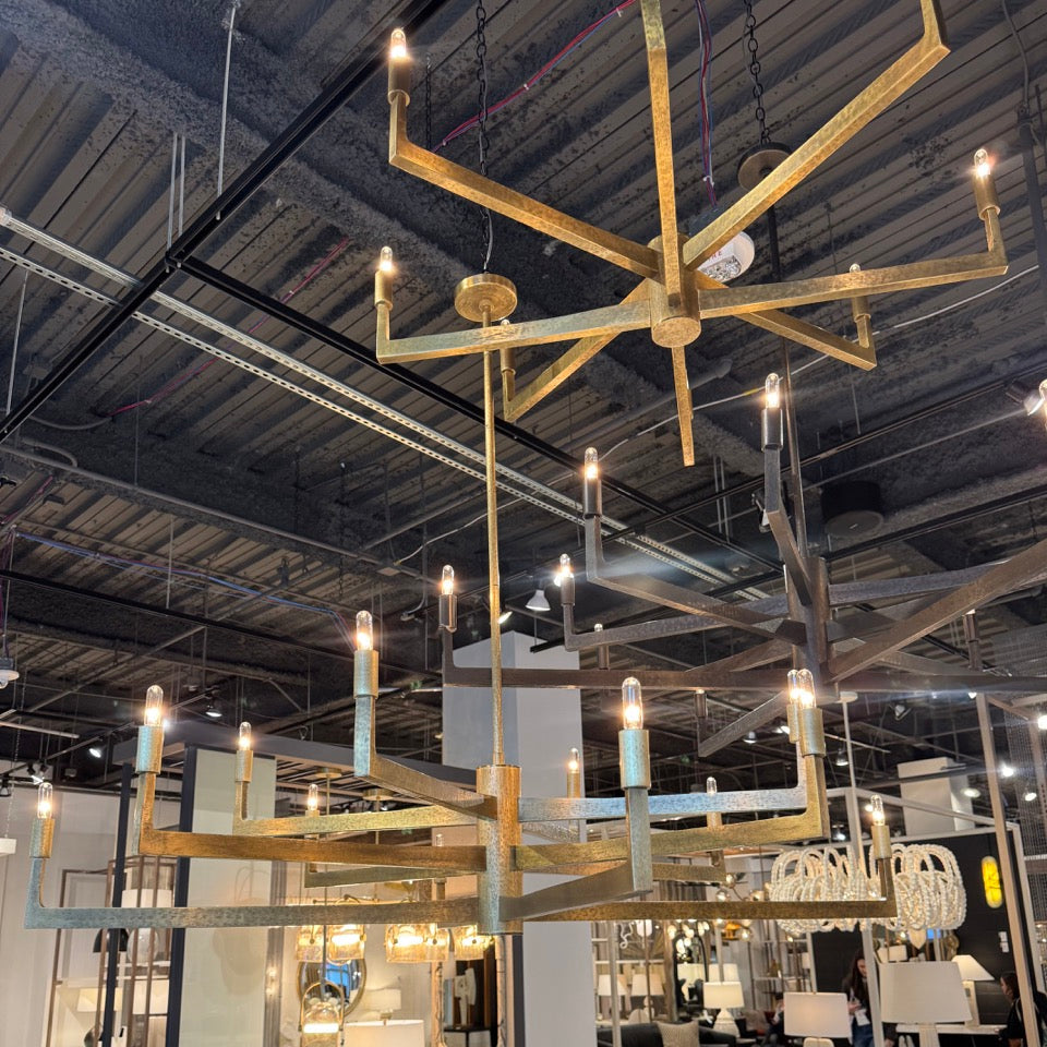 Gold chandelier in a showroom with various furniture and decor items.