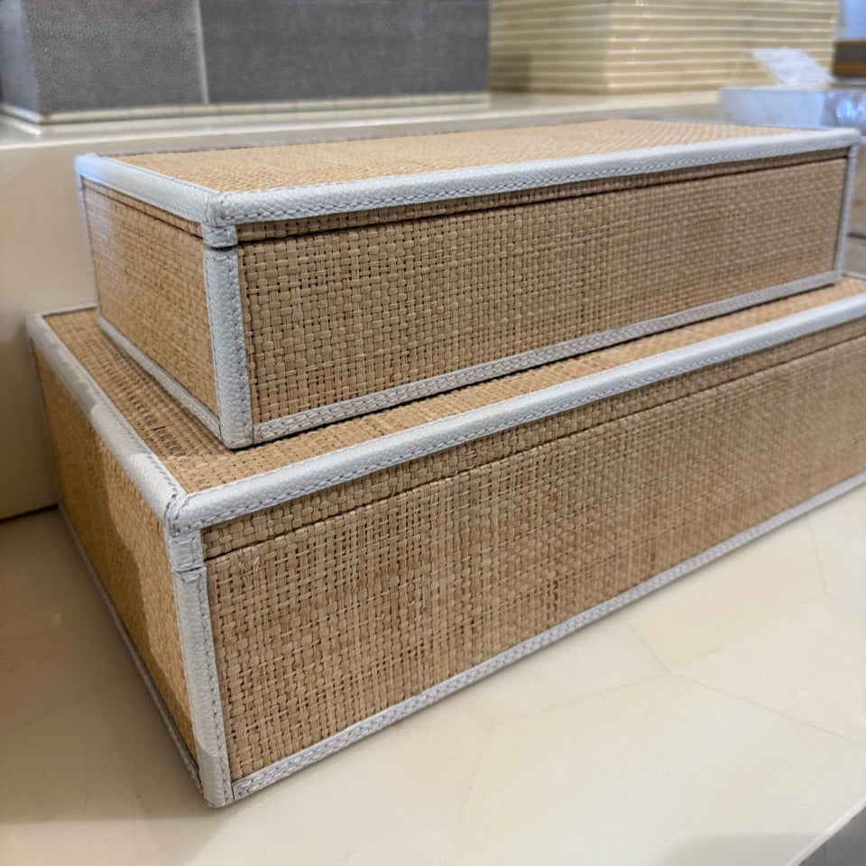 Two woven storage boxes with white lids on a light surface.