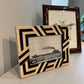Two decorative picture frames on a surface with a plain background