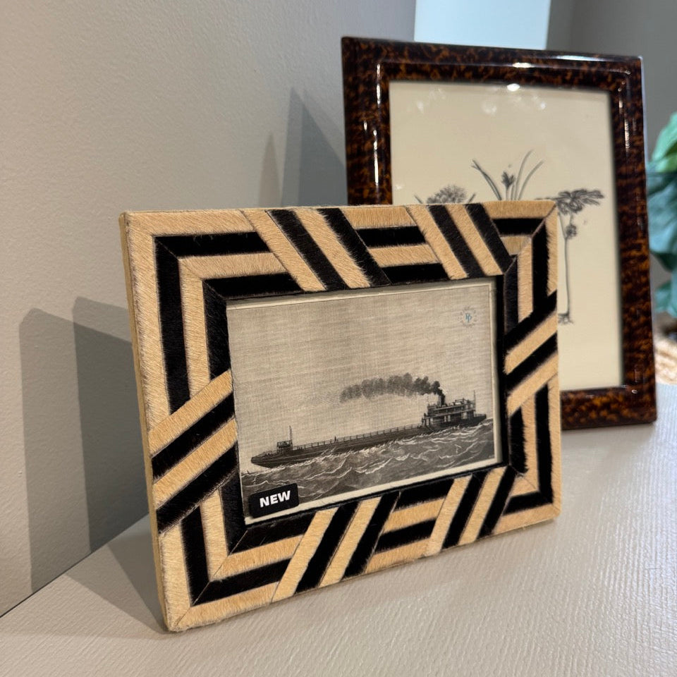 Two decorative picture frames on a surface with a plain background
