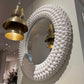 Decorative mirror with white textured frame and gold pendant light in a store setting