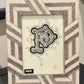 Decorative picture frame with geometric pattern and central monogram design on a plain background.