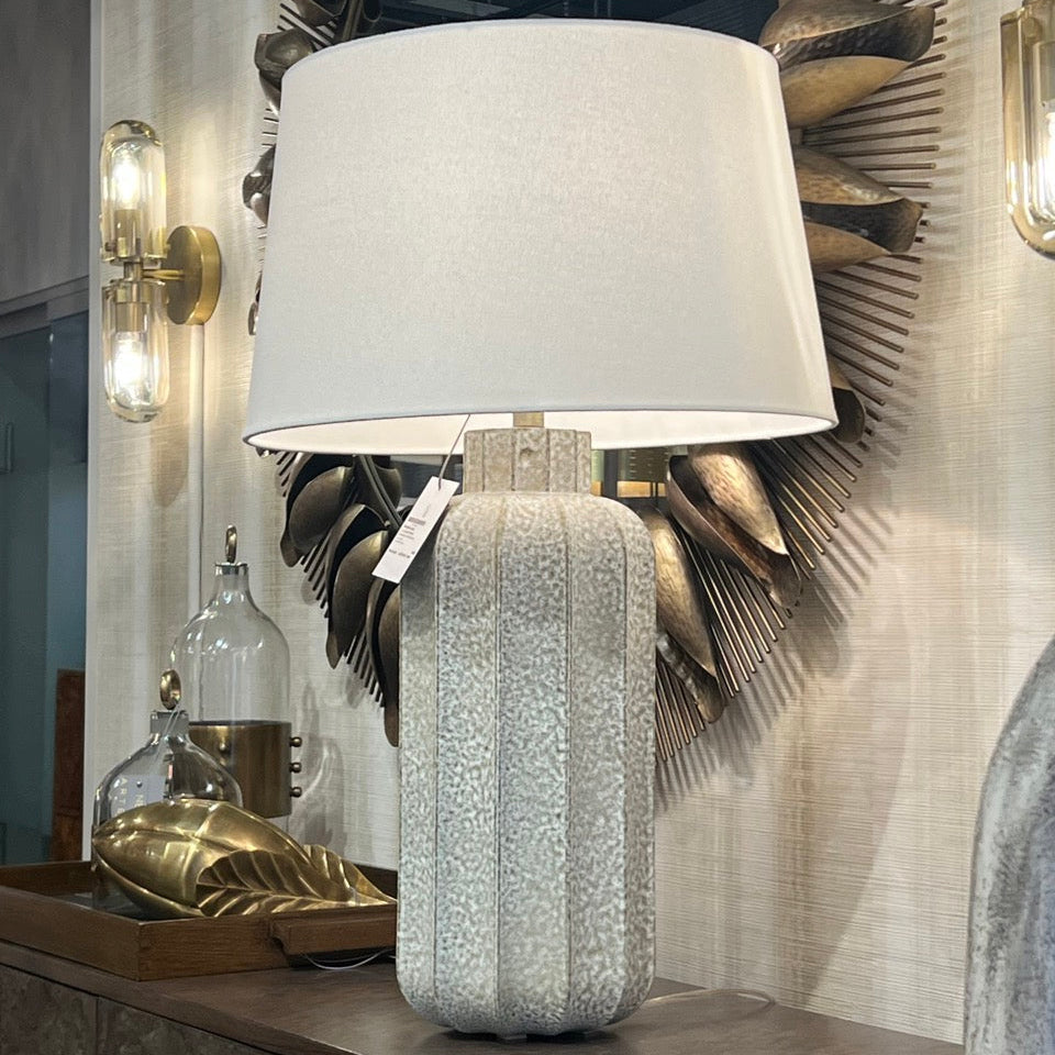 Decorative table lamp with textured base and white shade in a stylish interior setting.