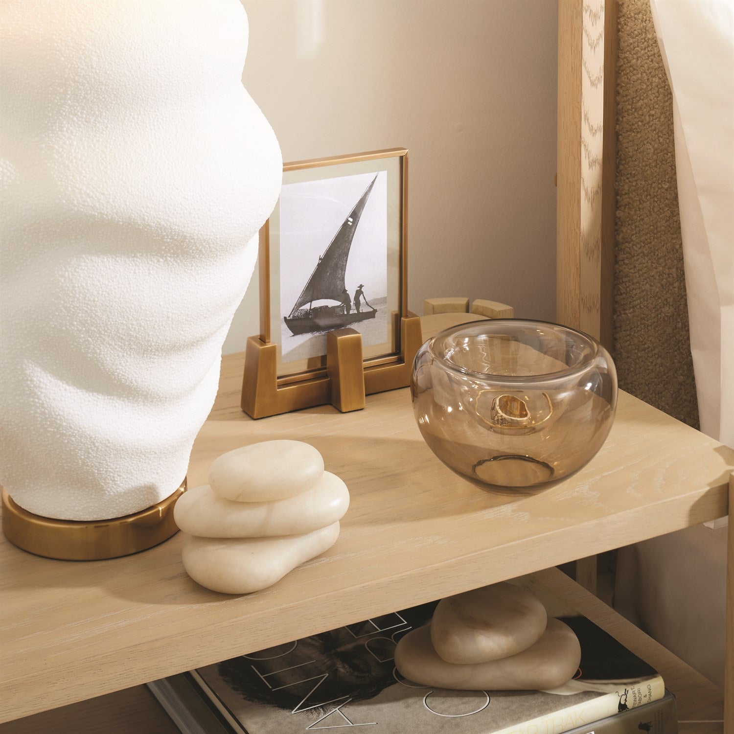 Decorative items on a wooden shelf including a glass bowl, framed picture, and stone sculptures.